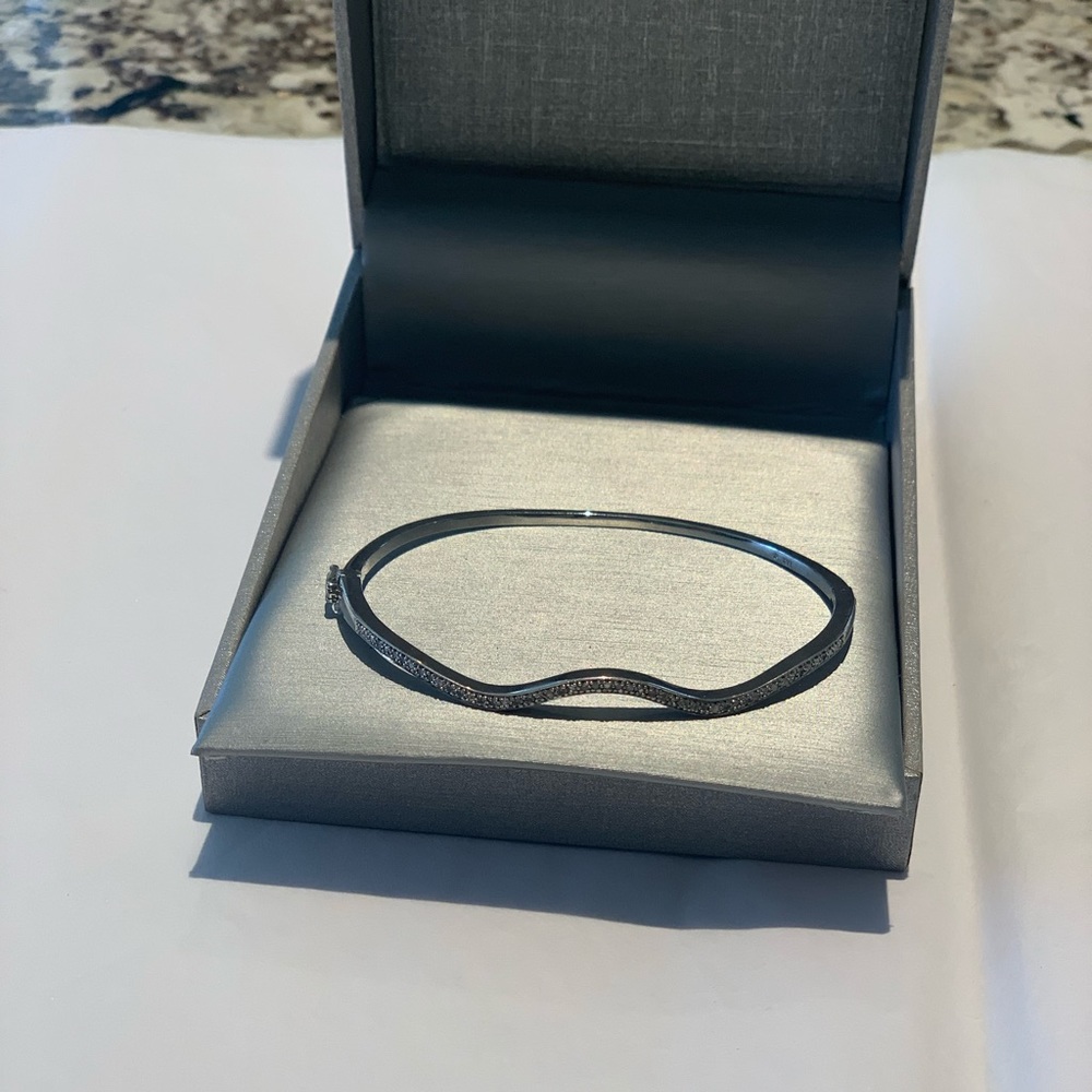 Sterling silver wavy bangle with diamond accents.